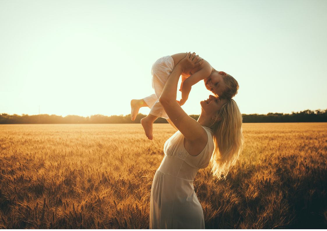 Madre alzando a su bebé, felices al aire libre