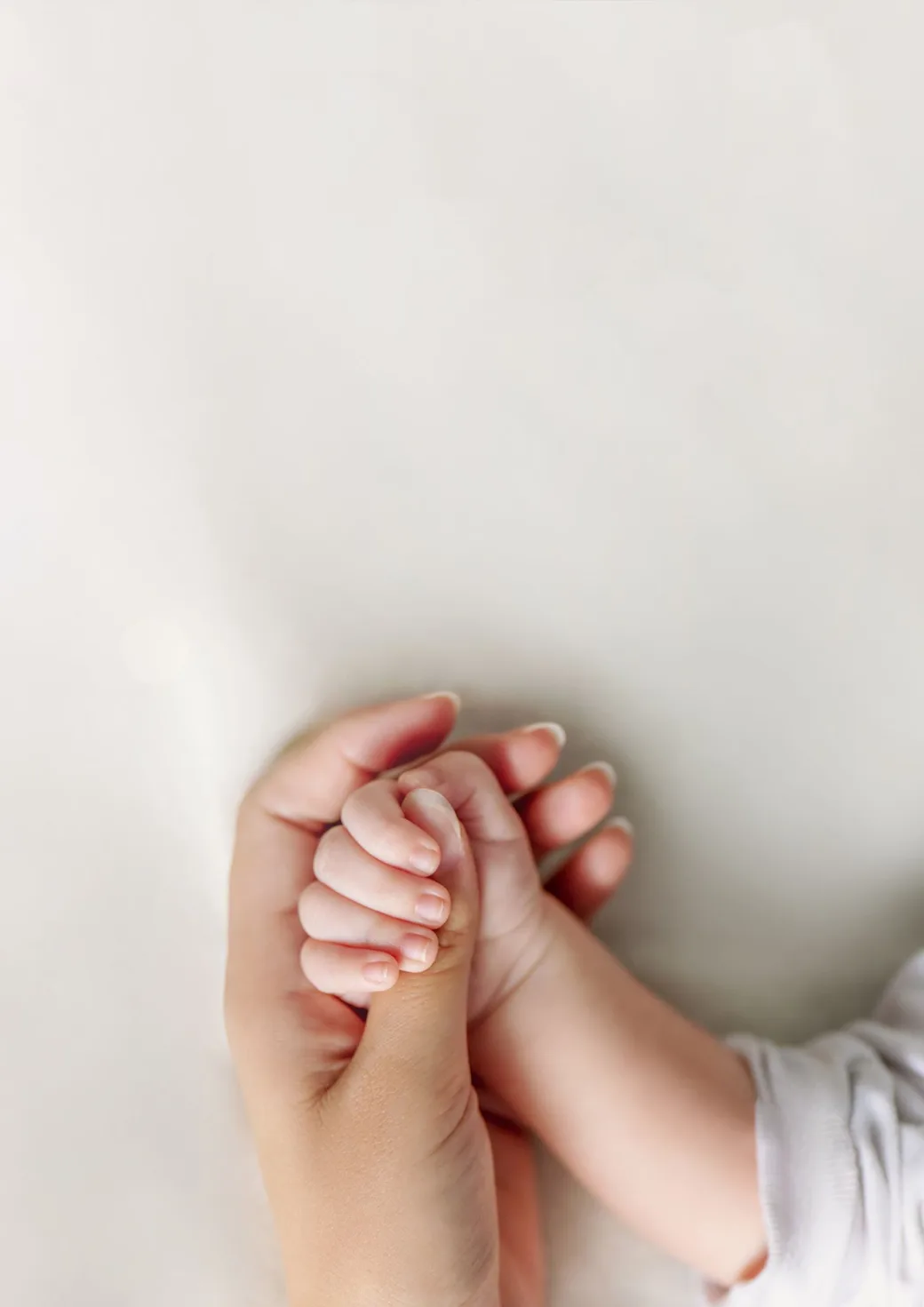 Mãozinha de bebê recém-nascido segurada pela mão da mãe — Memima, app de estimulação musical e educação auditiva para bebês de 0 a 6 anos
